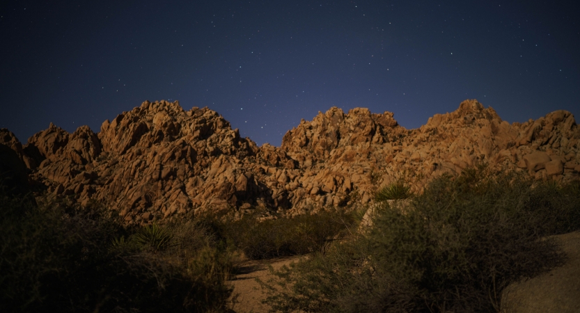 A rock formation lies under a dark blue sky. 